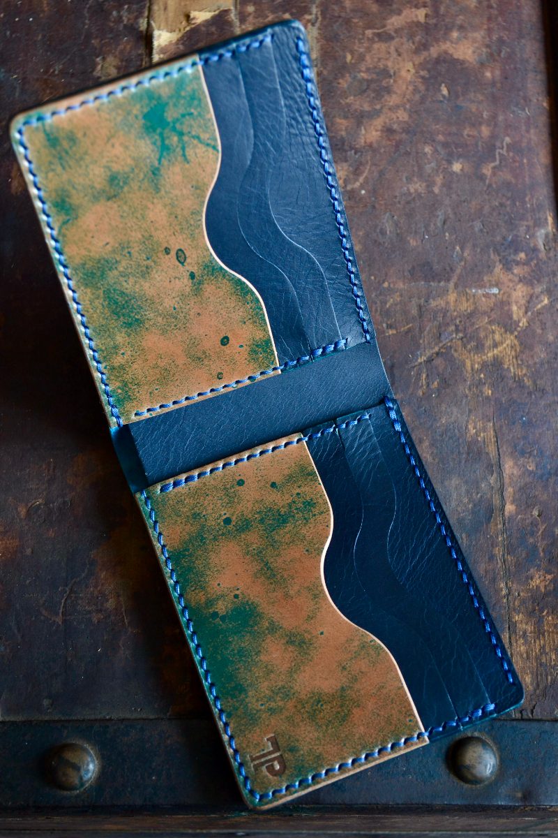 Navy bifold wallet open, showing marbled interior and stamped logo